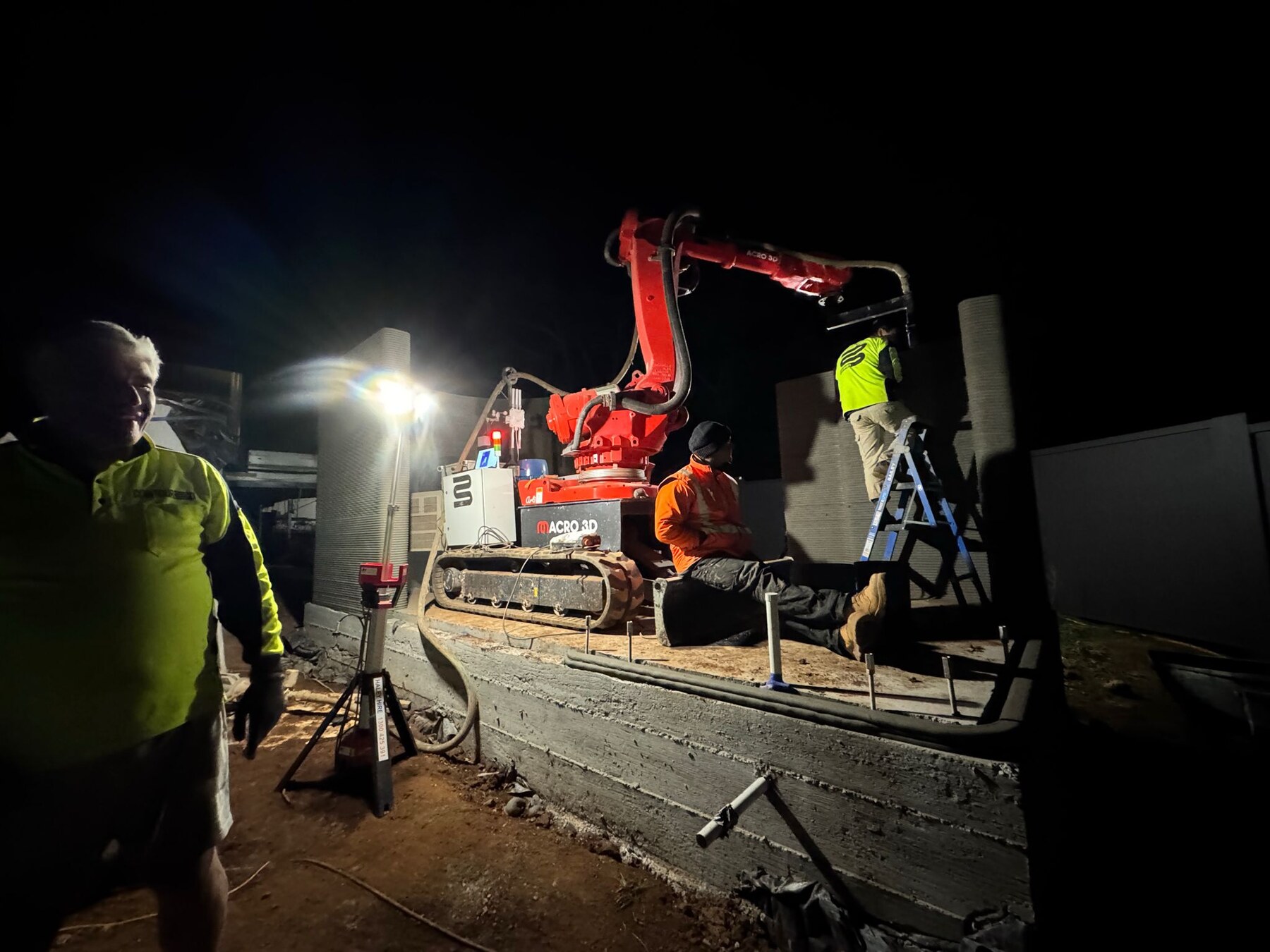 Macro3D red robot printing on site at night